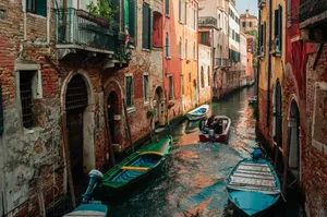A vibrant view of boats navigating through a classic Venice canal surrounded by historic buildings. jigsaw puzzle