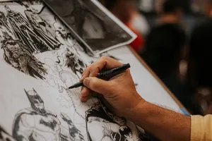 Artist drawing detailed comic book characters with a pen at a lively event. jigsaw puzzle