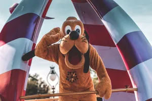 Playful Pluto character waving during a sunny Orlando parade at an amusement park. jigsaw puzzle