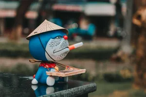Colorful figurine of a character wearing a Vietnamese hat and holding a cigarette outdoors. jigsaw puzzle