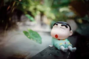 Adorable cartoon figurine sitting among green plants outdoors. jigsaw puzzle