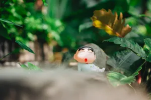 Toy figure resembling a cartoon character among vibrant green plants creating a playful outdoor scene. jigsaw puzzle