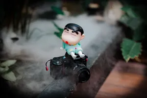 Cartoon figurine perched atop a vintage camera in a misty outdoor setting. jigsaw puzzle