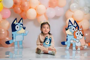 Young girl sitting with cartoon characters at a festive balloon-themed party. jigsaw puzzle