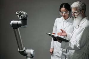 Researchers in lab coats and safety glasses engaging with a robotic arm in a lab setting. jigsaw puzzle