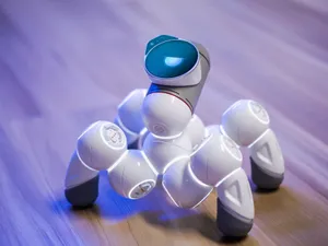 A sleek, white robotic toy on a wooden floor with a blurred background and blue lighting. jigsaw puzzle