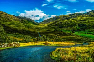 A beautiful rural landscape showcasing rolling hills, a winding road, and a vibrant summer sky. jigsaw puzzle