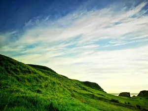 Beautiful green hillside landscape with dramatic clouds and clear blue sky. jigsaw puzzle