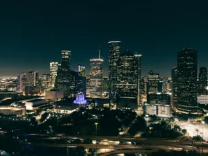 Aerial view of a vibrant city skyline at night with illuminated skyscrapers and roads. jigsaw puzzle