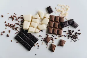 An artistic flat lay of assorted dark, white, and milk chocolate bars with chocolate crumbles. jigsaw puzzle