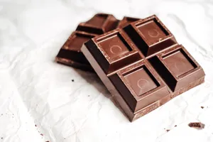 Delicious dark chocolate bars showcased in a close-up shot on white paper, emphasizing texture and detail. jigsaw puzzle