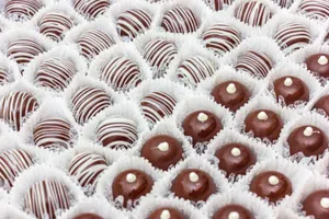 Close-up of assorted chocolate truffles arranged in decorative white wrappers, perfect for dessert displays. jigsaw puzzle