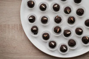 Top-down view of assorted chocolate pralines elegantly arranged on a white plate. jigsaw puzzle