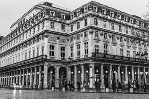 Black and white photo of a classic Parisian building with columns and pedestrians. jigsaw puzzle