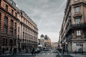 Urban street scene in Paris with classic architecture, cars, and pedestrians on an overcast day. jigsaw puzzle