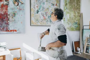 An artist painting on a canvas in a studio, surrounded by abstract artwork. jigsaw puzzle