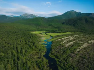 Stunning aerial view of a lush green valley with a winding river and distant mountains. jigsaw puzzle