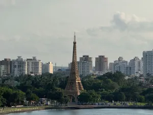 Replica of the Eiffel Tower surrounded by a modern city skyline in a lush green park. jigsaw puzzle