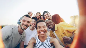 A diverse group of friends taking a joyful selfie outdoors during sunset. jigsaw puzzle