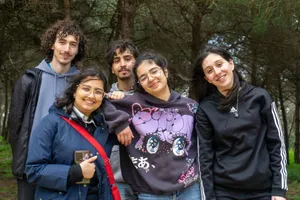 A joyful group of young adults smiling together in a serene forest setting, enjoying a day outdoors. jigsaw puzzle