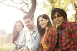 A diverse group of friends sitting outdoors, smiling and enjoying a sunny day. jigsaw puzzle