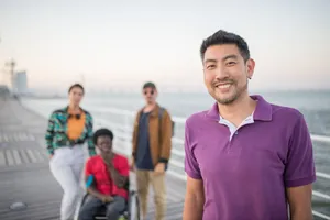 A diverse group of friends smiling together on a seaside boardwalk in Lisbon, Portugal during the day. jigsaw puzzle