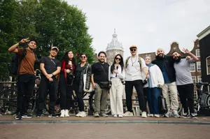 Diverse group of tourists posing in Amsterdam with a historic building backdrop. jigsaw puzzle