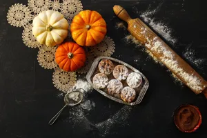 Flat lay of pumpkins, pastries, rolling pin, and sieve on a dark surface. jigsaw puzzle