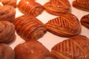Close-up view of various golden pastries with icing, displayed in rows. jigsaw puzzle