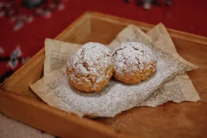 Freshly baked cream puffs dusted with icing sugar on a wooden tray, perfect for a cozy treat. jigsaw puzzle