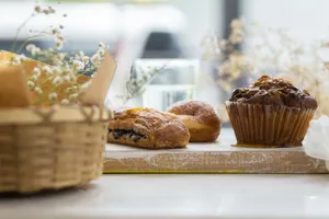 A delectable assortment of pastries including a muffin and croissant on a rustic wooden board. jigsaw puzzle