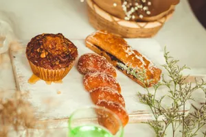 A delectable variety of pastries including muffin, donut, and pastry roll on a rustic wooden board. jigsaw puzzle