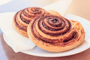 A close-up view of two freshly baked cinnamon rolls served on a white plate. jigsaw puzzle