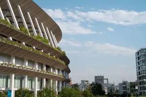 A striking view of Tokyo National Stadium featuring greenery and modern design against a clear sky. jigsaw puzzle