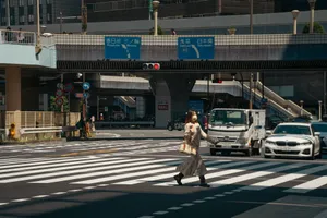 A woman in Tokyo crosses a busy street under a clear sky, highlighting urban life and traffic. jigsaw puzzle