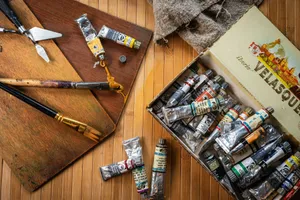 Artistic setup featuring various paint tubes, brushes, and tools on a wooden surface. jigsaw puzzle