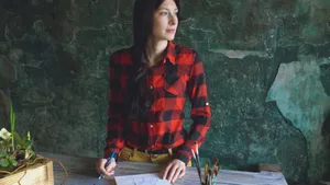 Woman in red plaid shirt sketching at a wooden table, exuding creativity. jigsaw puzzle