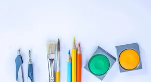 A vibrant collection of art supplies including brushes, pencils, and paints on a white background. jigsaw puzzle