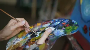 Close-up of an artist's hand mixing vivid colors on a palette using a brush. jigsaw puzzle