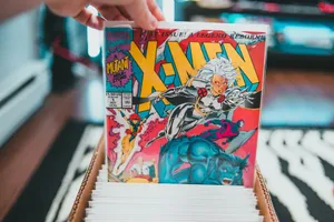 Crop anonymous person demonstrating collection of colorful comic books placed in box in living room jigsaw puzzle
