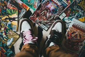 From above crop person wearing brown trousers and sneakers standing on pile of collection of comics magazines with colorful illustrations on cover jigsaw puzzle