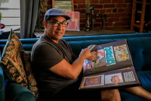 Man in hat and glasses proudly displaying his colorful graffiti art portfolio on a couch. jigsaw puzzle