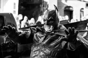 A street performer dressed as Batman engaging with the crowd in a lively urban setting. jigsaw puzzle