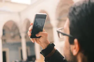 An adult male photographs a mosque using a smartphone outdoors with a focus on capturing architecture. jigsaw puzzle