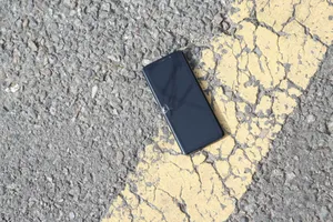 A close-up view of a cracked smartphone lying on a sunlit asphalt road. jigsaw puzzle