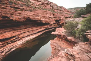 Picturesque view of rough rocky formations with green vegetation near water in ravine jigsaw puzzle