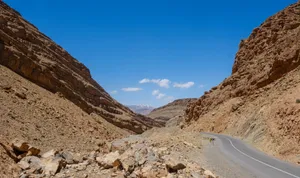 A breathtaking view of a winding road through the rocky Atlas Mountains under a clear blue sky in Morocco. jigsaw puzzle