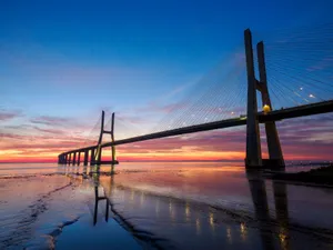 Stunning sunset over Vasco da Gama Bridge reflecting in the waters of Lisbon's coast. jigsaw puzzle