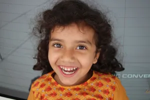 Adorable South Asian girl with curly hair, joyfully smiling outdoors. jigsaw puzzle