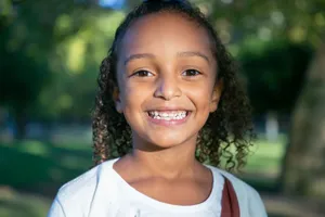 Bright portrait of a curly-haired girl smiling outdoors in sunny Portugal park. jigsaw puzzle